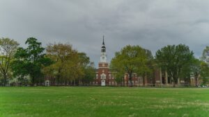 Dartmouth College’s Baker-Berry Library with its iconic bell tower, framed by a green lawn and trees under a cloudy sky.